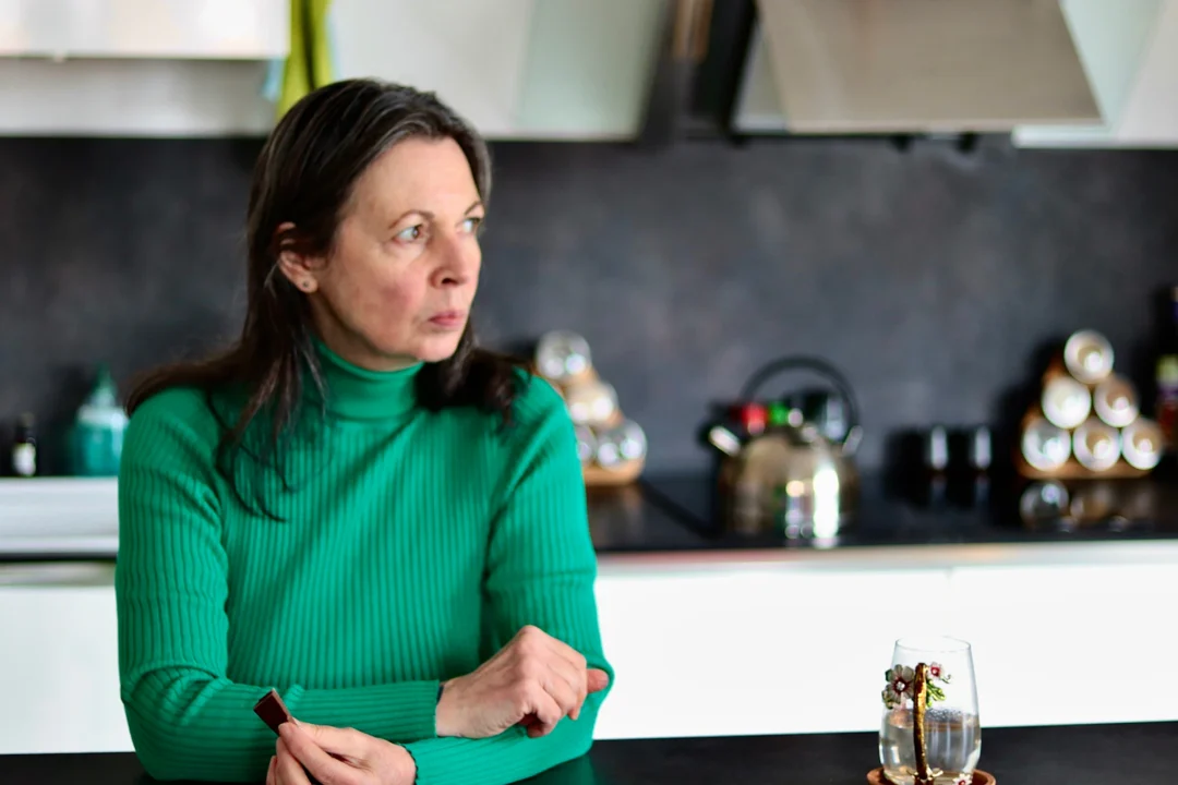Donna seduta al tavolo della cucina con aria pensierosa