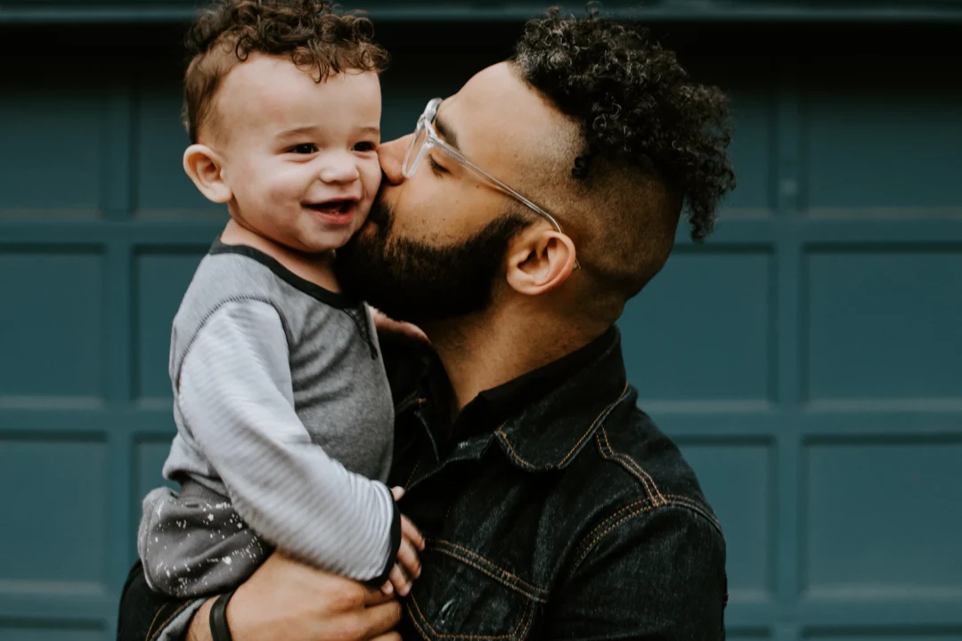 Padre che bacia sulla guancia il figlio piccolo che sorride
