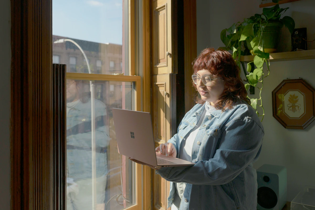 Donna al computer davanti alla finestra mentre controlla una pratica online