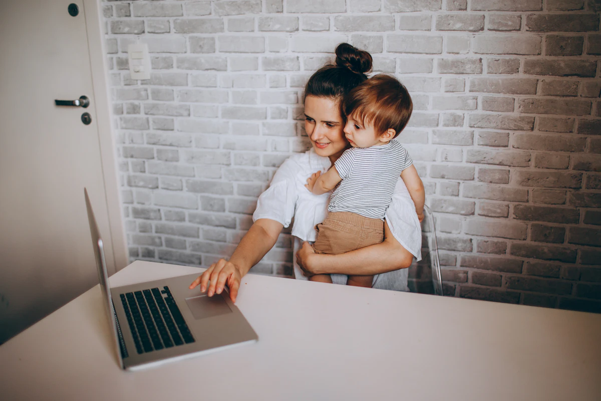 Madre al computer con il figlio piccolo in braccio