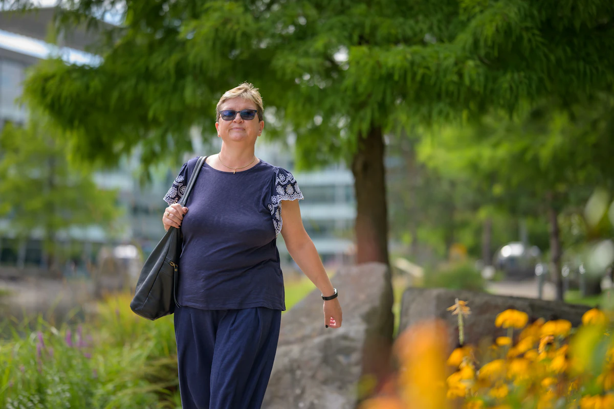 Donna che cammina in un parco con una borsa a tracolla