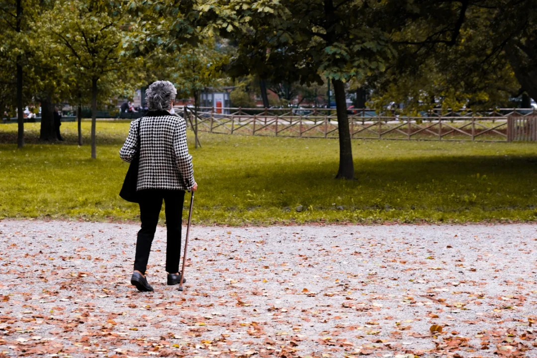 Donna anziana che cammina in un parco in autunno