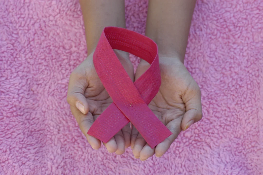 Mani che tengono il nastro rosa, simbolo di Ottobre rosa e della prevenzione del tumore al seno