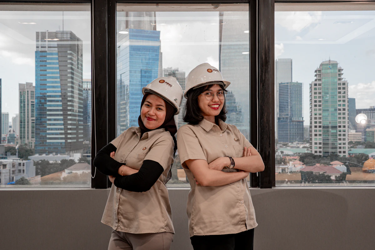 Due donne con elmetto e divisa da lavoro in un ufficio con vista sulla cittร