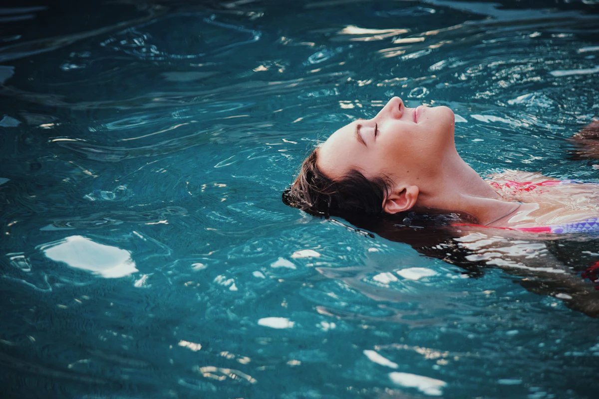 Donna che galleggia rilassata nell'acqua di una piscina