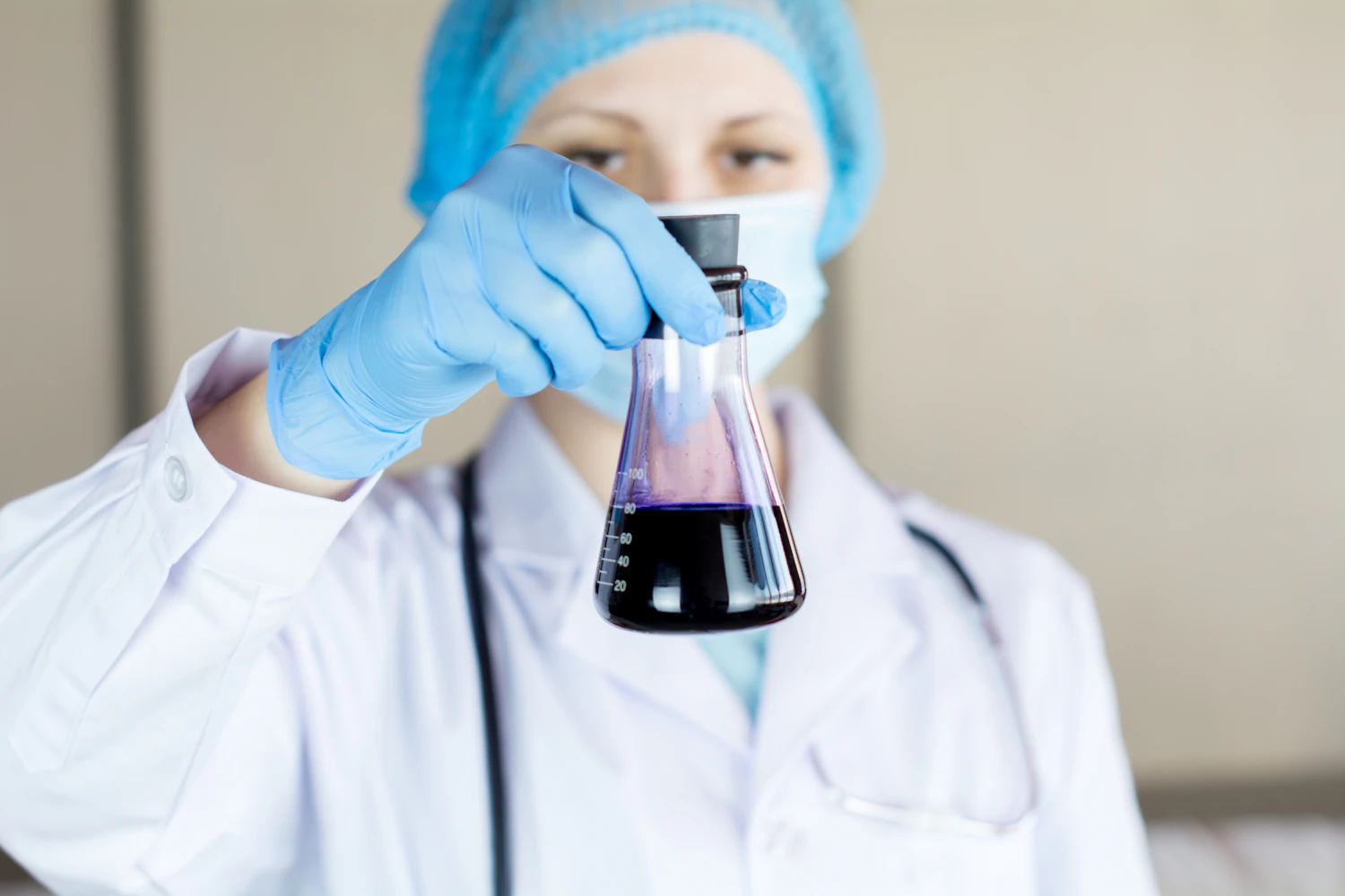 Ricercatrice in camice bianco che osserva una fiaschetta in laboratorio
