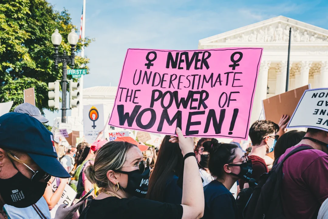 Manifestanti con un cartello rosa con la scritta Never underestimate the power of women