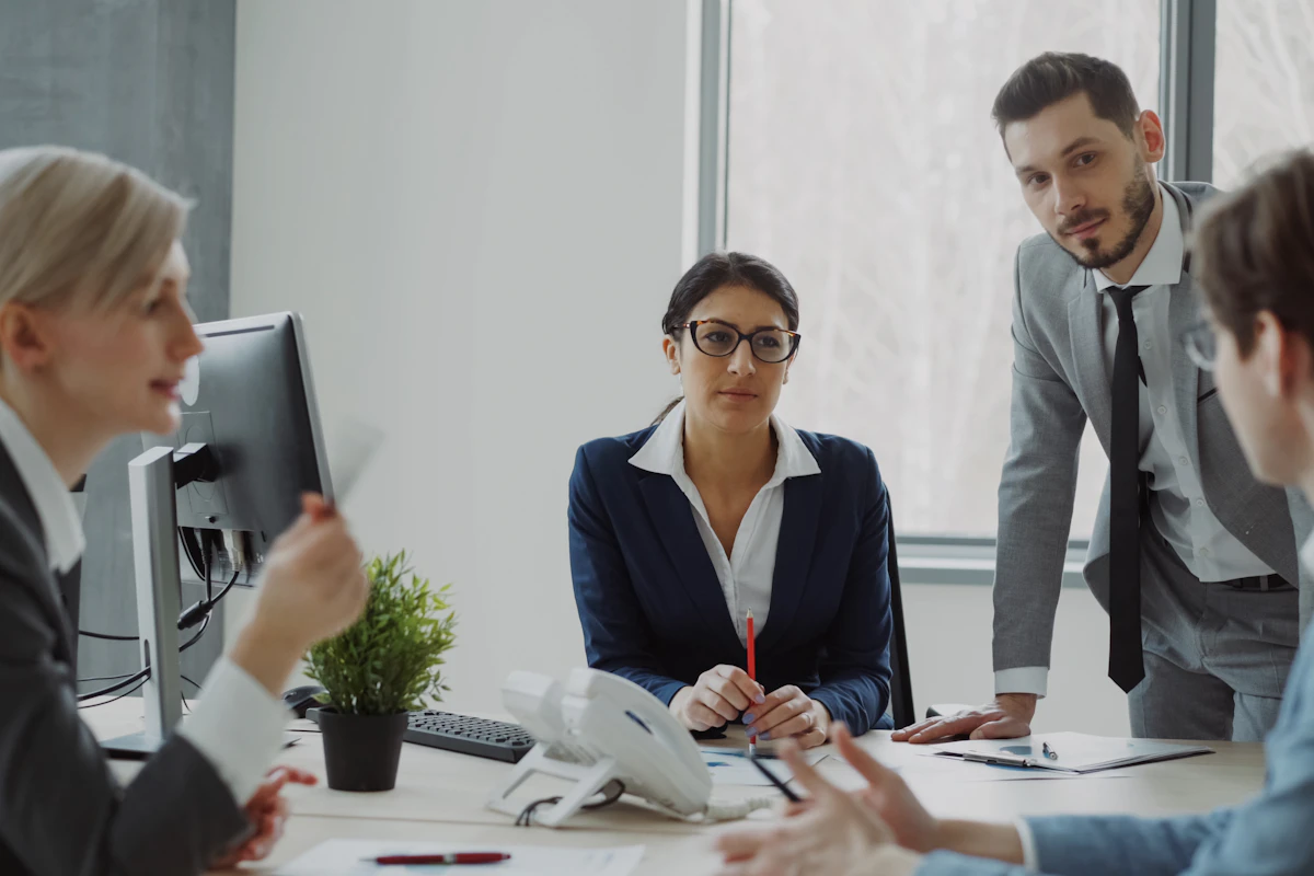 Donna che parla durante una riunione di lavoro con colleghe e colleghi