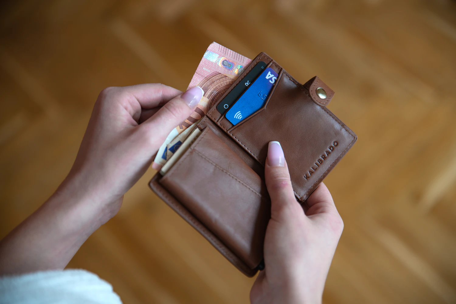 Mani di donna che tengono un portafoglio con una carta, simbolo dell'autonomia economica